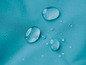 Waterdruppels op een turquoise textiel oppervlak.