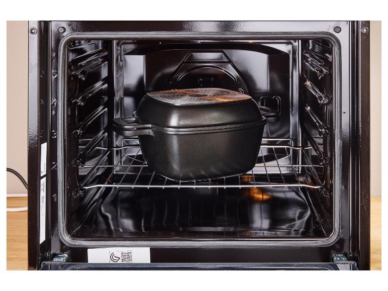Open oven met een zwarte kookpot op het rooster.