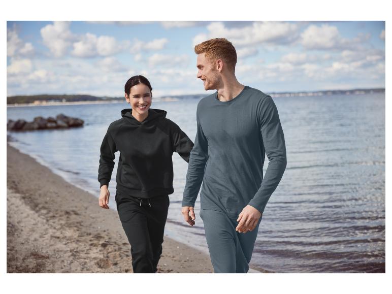 Un homme et une femme en sweat-shirts noirs et pantalons de survêtement sur la plage.