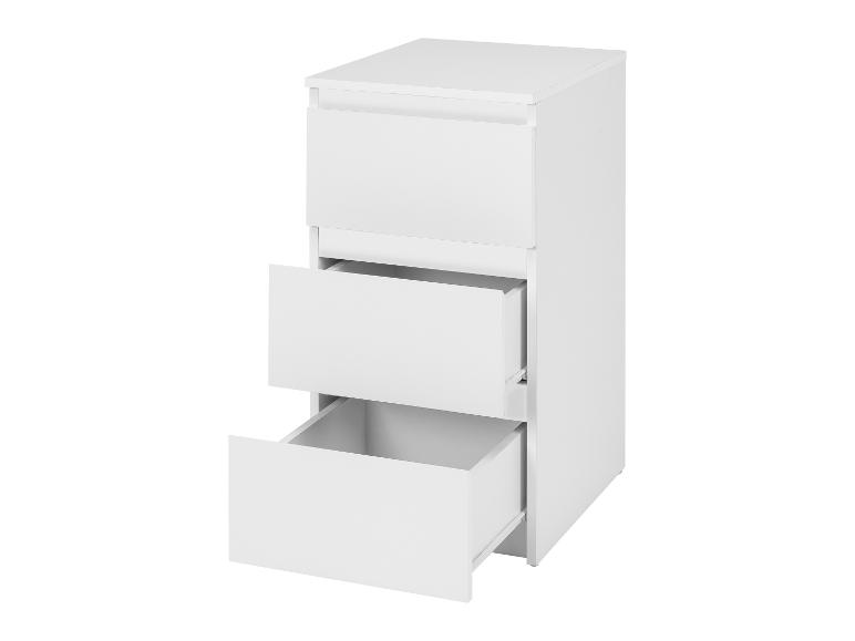 Une commode blanche à trois tiroirs, un est ouvert.