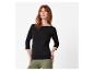 Femme rousse en haut noir à manches trois quarts et pantalon kaki.