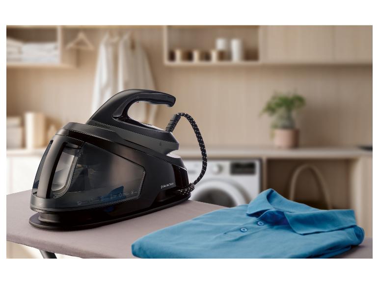 Centrale vapeur sur une planche à repasser avec une chemise bleue pliée.