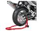 Arrière d'une moto sur un support rouge, montrant pneu, chaîne et échappement