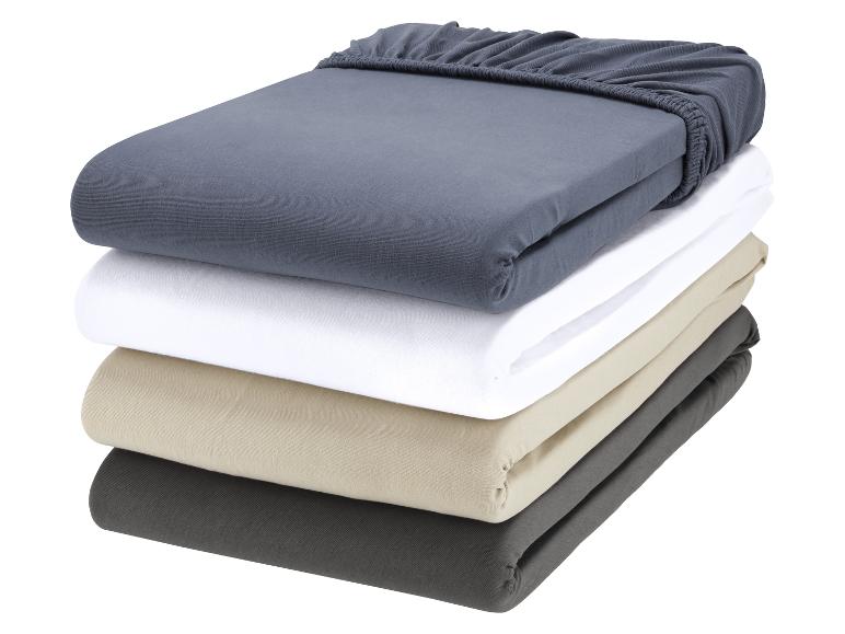 Une pile de quatre draps jersey de différentes couleurs.