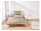 Beige beddengoed met geometrisch patroon op een bed.
