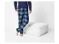 Homme en pyjama à carreaux bleus et noirs à côté d'un pouf blanc.