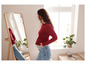 Une femme enceinte portant un pull rouge et un jean bleu regarde dans un miroir.