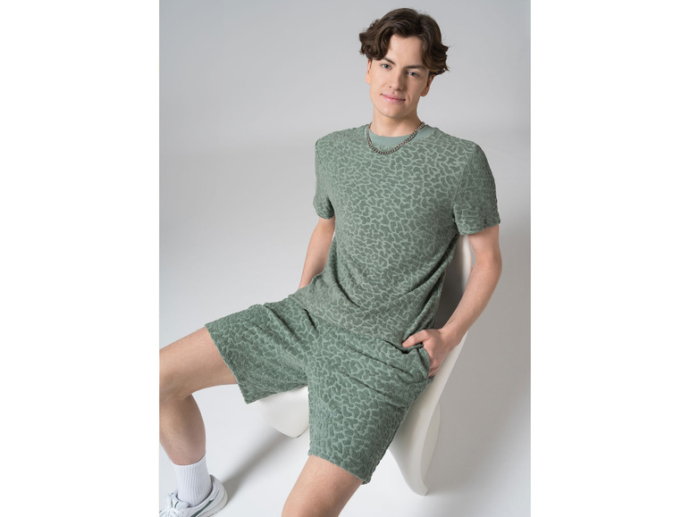 Man draagt een groene T-shirt en korte broek met luipaardprint.
