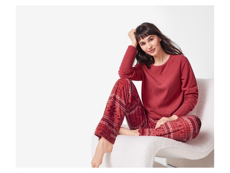 Vrouw in rode pyjama met patroon, zittend op een witte stoel.