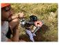 Homme cuisinant en extérieur avec un grill portable, une lanterne et une salade fraîche sur une table de camping.