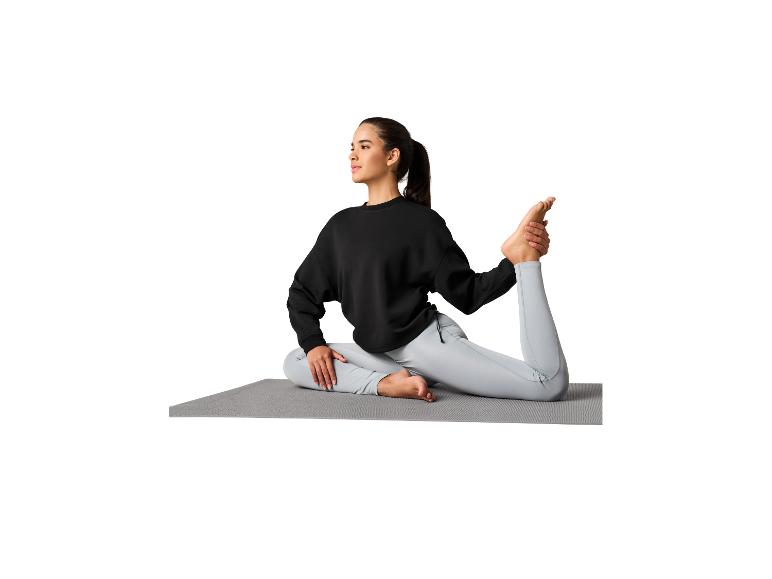 Vrouw in zwarte sweater en lichtgrijze legging op yogamat