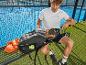 Man op padelbaan met padelracket, rugzak, handdoek en waterfles.