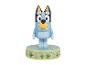 Figurine de chien bleu de dessin animé sur une base verte avec un thème de jardin.