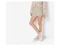 Beige shorts en vest van breiwerk, met sneakers.