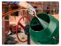 Gehandschoende hand giet water uit een slang in een groene betonmolen op een bouwplaats.