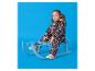Petite fille en combinaison à motifs assise sur une luge bleue.