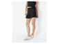 Vrouw in zwarte top en zwarte ruffle skort, witte sneakers.