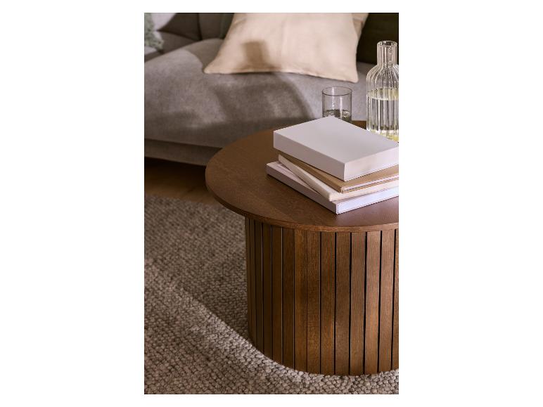 Table basse ronde en bois avec livres et bouteille d'eau dans le salon.