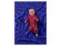 Bébé heureux en grenouillère rouge allongé sur une couverture gaufrée bleue