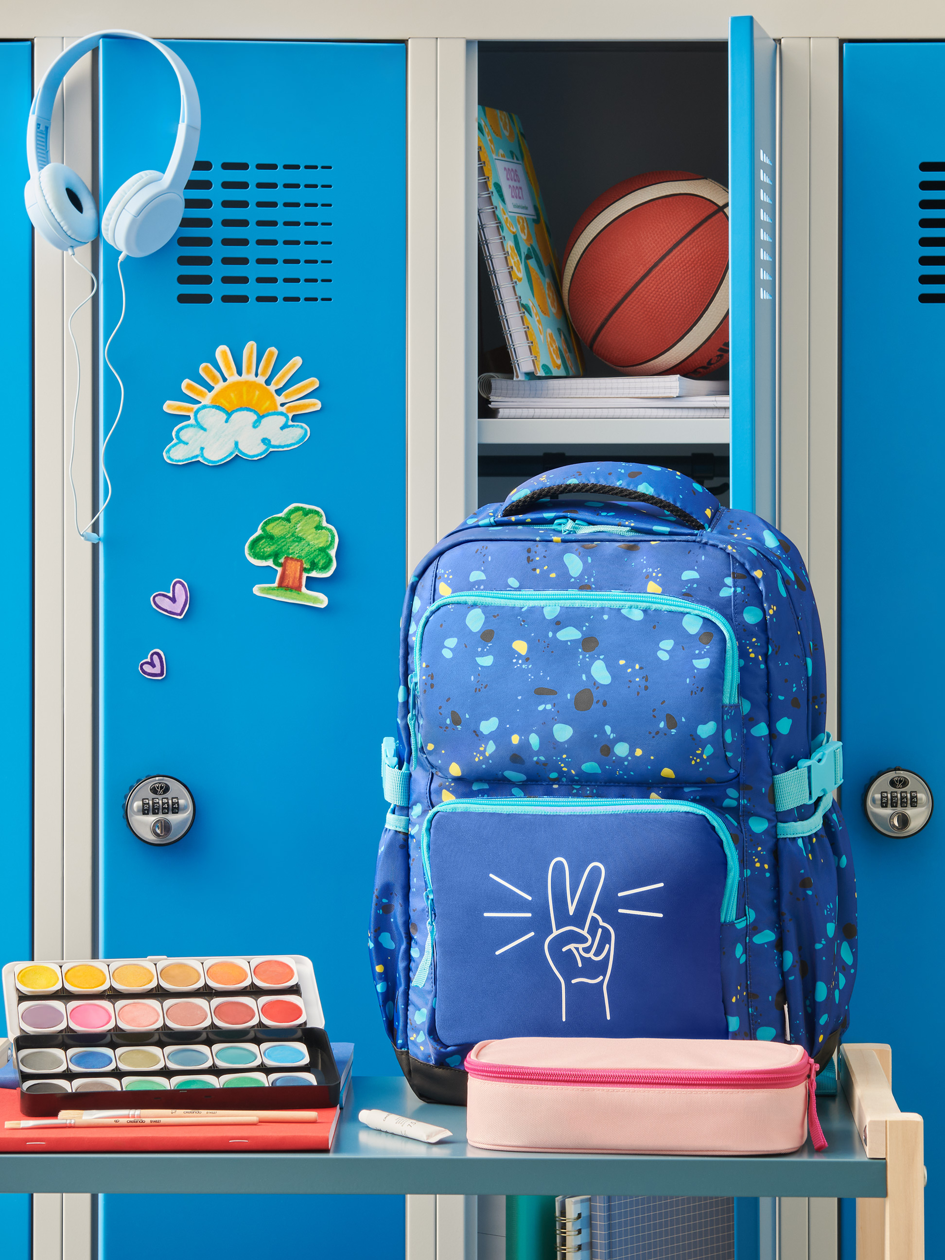 Blauwe rugzak met vredesteken, koptelefoon, waterverf en schoolspullen in een kluisje.