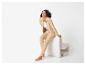 Vrouw in beige trainingspak en witte top zittend, lachend