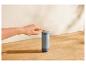 Hand drukt op een knop op een grijze SilverCrest thermosfles op een houten aanrecht.