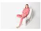 Vrouw in roze luipaardprint pyjama, zittend op een witte stoel.
