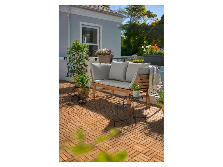 Houten terras met een houten bank met grijze kussens, planten en bloemen in potten.