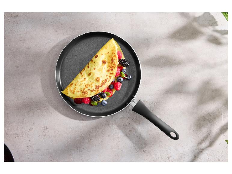 Crêpière avec une crêpe pliée garnie de baies fraîches et de feuilles de menthe.