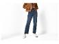 Personne portant une veste en daim marron, un jean bleu foncé et des baskets blanches.