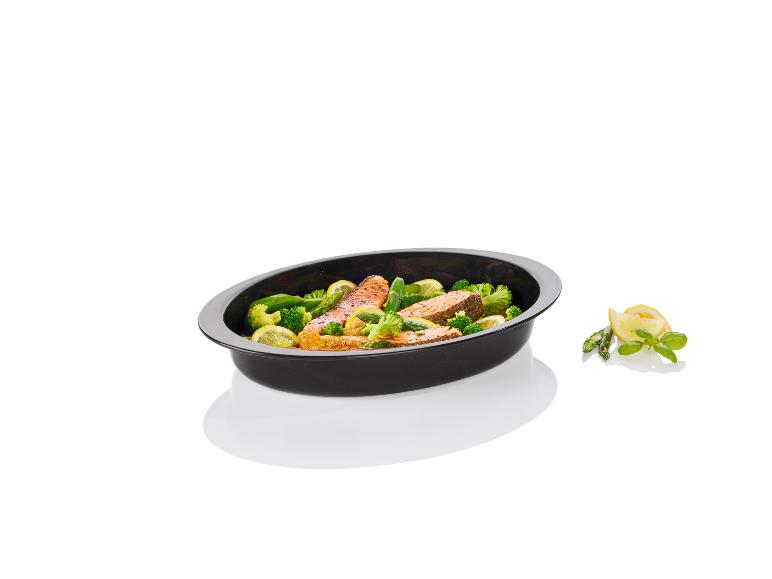 Een ovaal bakblik met gebakken zalm, broccoli en asperges.