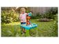 Fille joue avec une table eau-sable avec moulin et bateaux dans le jardin.