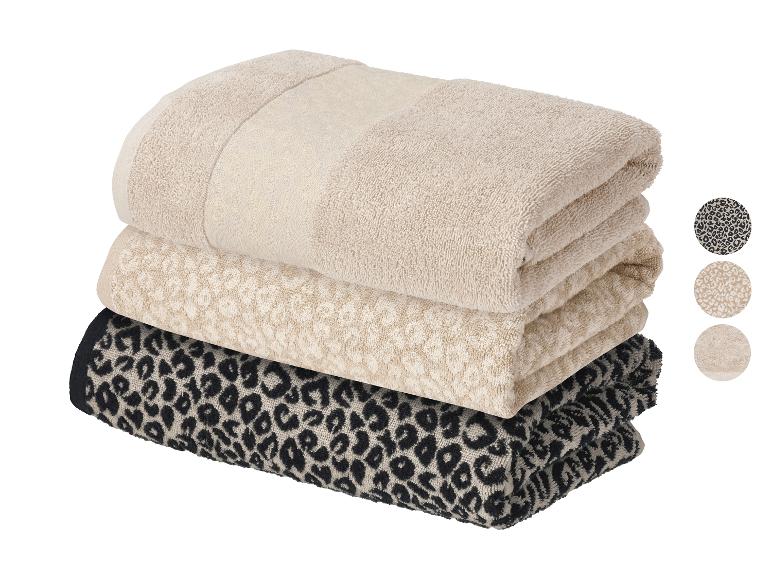 Stapel van drie handdoeken: effen beige, beige met luipaardprint en zwart met luipaardprint.