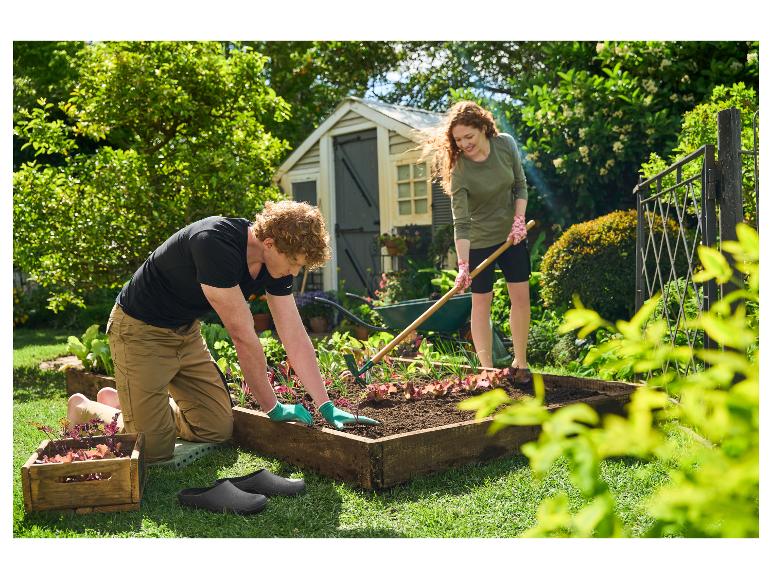 Un homme et une femme plantent dans le jardin, l'homme porte des sabots noirs.