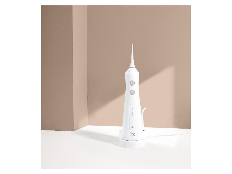 Witte Cien Beauty monddouche op een oplaadstation, met beige achtergrond