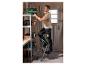 Man op ladder plaatst groene gereedschapskist op metalen rek.