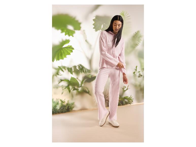 Femme en ensemble deux pièces côtelé rose clair avec un sweat à capuche et un pantalon large.