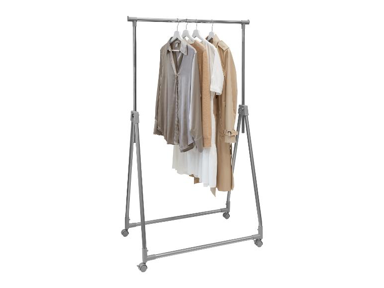 Chemise, pull et trench beige sur un portant mobile.