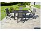 Table et quatre chaises de jardin gris foncé sur une terrasse en bois avec jardin.