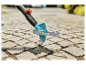 Outil de désherbage en action sur un pavé.