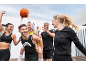 Famille et amis jouant au basketball, vêtus de vêtements de sport Crivit noirs et jaunes.