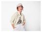 Femme rousse portant une veste beige, un t-shirt rayé et un pantalon blanc.