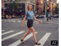 Une femme en t-shirt bleu et short en jean noir traverse sur un passage piéton en ville.