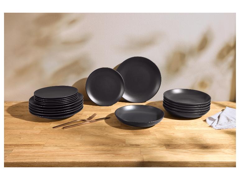 Assiettes en céramique noir mat avec couverts en cuivre sur une table en bois.