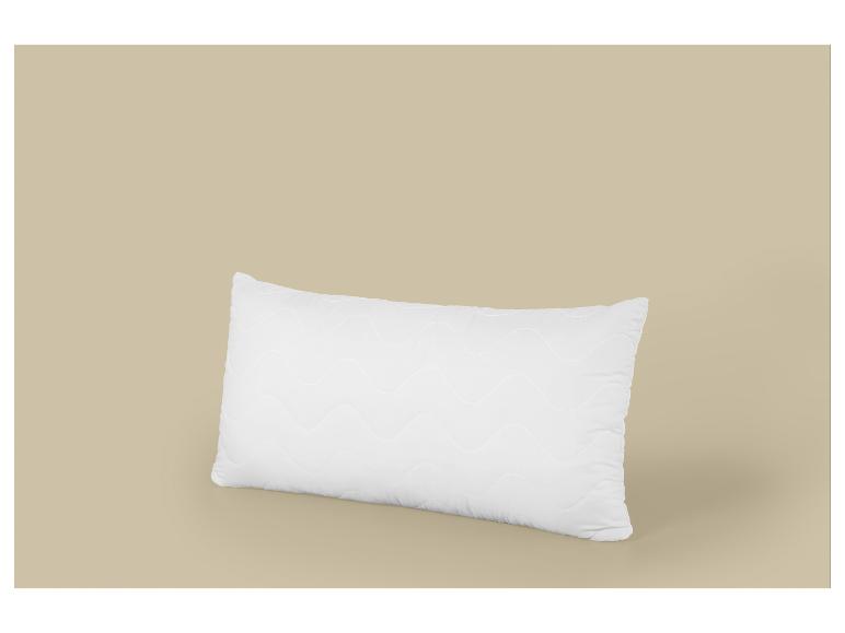 Oreiller blanc rectangulaire avec motif ondulé sur fond beige