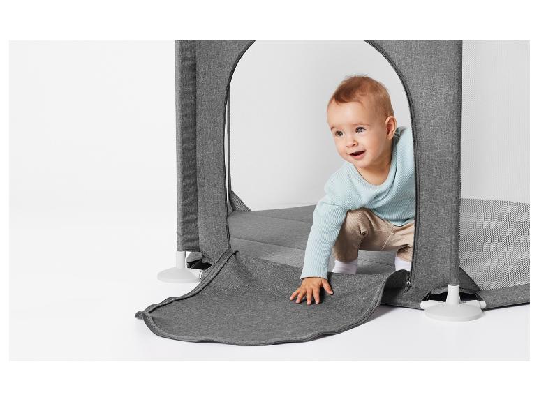 Een baby in een grijze speelomheining met gaas.
