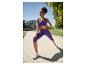 Vrouw in paarse sportbeha en capri legging rekt zich uit buiten.