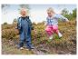 Twee blije kinderen in waterdichte jassen en tuinbroeken spelen in modderige plassen.