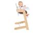 Baby in een houten kinderstoel met een wit dienblad, kijkt opzij.