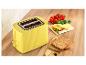 Grille-pain jaune SilverCrest, pain, fromage et tomates sur une table en bois.